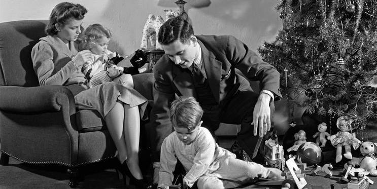 1930s 1940s FAMILY AROUND CHRISTMAS TREE BOY PLAYING WITH TRAIN DAD HELPING MOM AND GIRL IN CHAIR