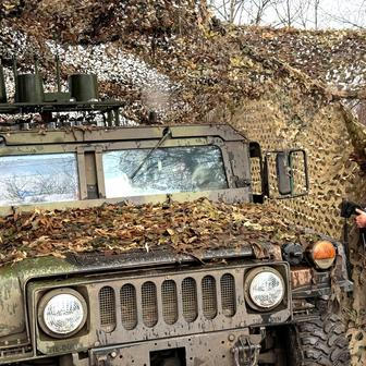 Ukrainian serviceman camouflages a HMMWV vehicle near the frontline city of Kupiansk