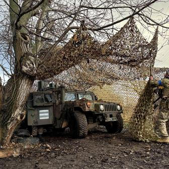 Ukrainian serviceman camouflages a HMMWV vehicle near the frontline city of Kupiansk
