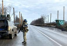 Ukrainian serviceman checks the sky for Russian combat drones as he stands at a road near the frontline city of Kupiansk