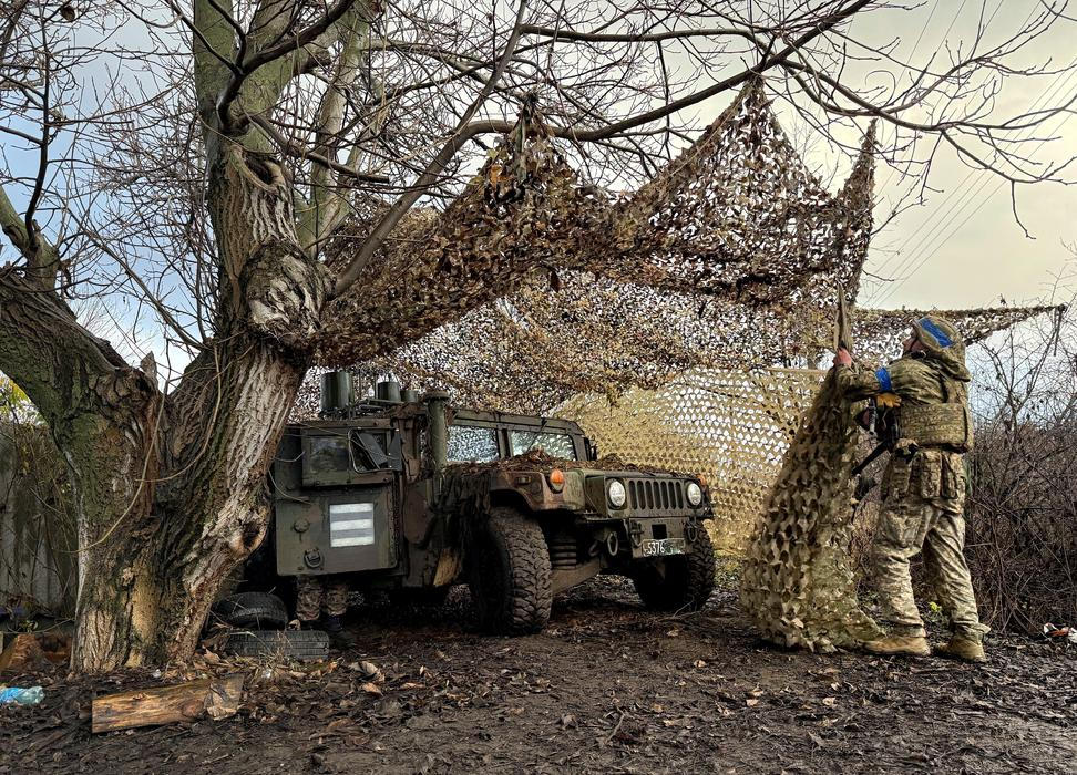Ukrainian serviceman camouflages a HMMWV vehicle near the frontline city of Kupiansk
