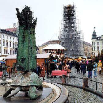 Arionova kašna, v pozadí vánoční trhy a památka UNESCO - sloup Nejsvětější trojice. Olomouc, 5. prosince 2025.