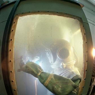 Podvodní svářeči opravují konstrukce pod hladinou za použití speciální techniky. Rizika zahrnují dekompresní nemoc a utonutí. Potápěč trénuje podvodní svařování v laboratoři Institutu elektrického svařování E. O. Patona v Kyjevě, Ukrajinská SSR, 70. léta.