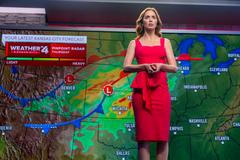 Emily Bluntová jako televizní hlasatelka počasí ve Spielbergově filmu Den odhalení.