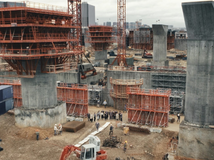 Když se děj filmu Architekt přesune na staveniště, kamera se zaměřuje na chaotickou masu dělníků, jeřábů, bláta a improvizace. 