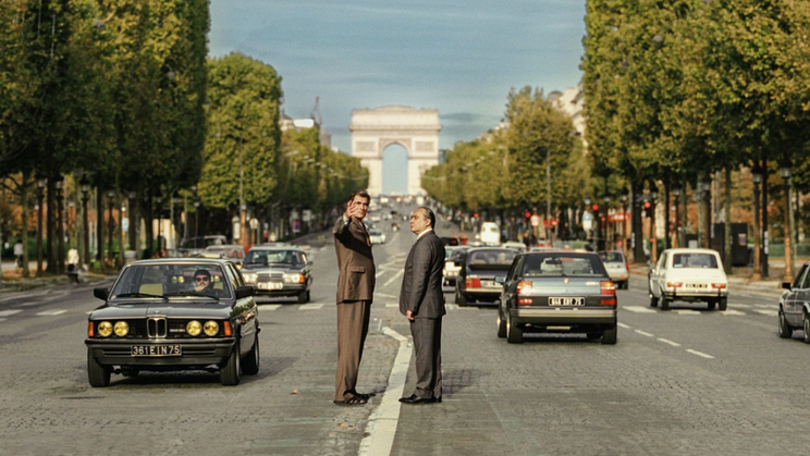 Claes Bang jako architekt Spreckelsen, který navrhl pařížský Velký oblouk, a Michel Fau ve filmu Architekt.
