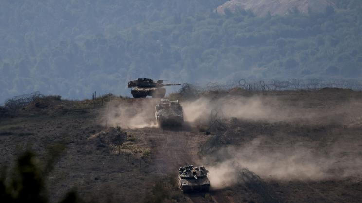 FILE PHOTO: Israeli military vehicles manoeuvre along the Israel-Lebanon border as seen from northern Israel