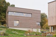 Jednoduchá kubická forma je sjednocena fasádou z horizontálního dřevěného obkladu. Ten zvýrazňuje kompaktnost hmoty. 