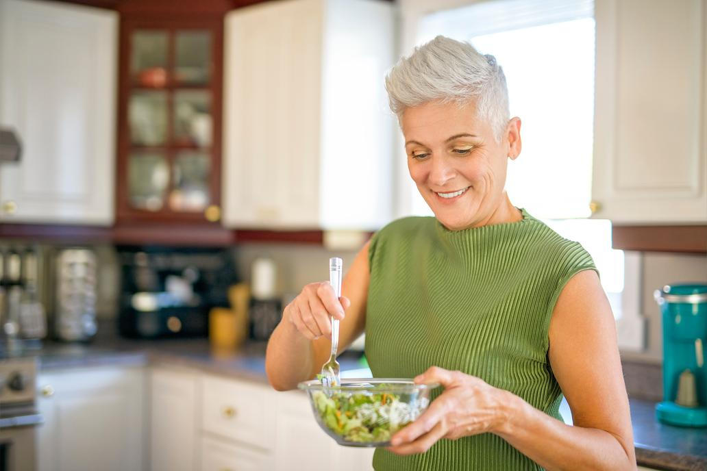 A,Mature,Smiling,Woman,Eating,Salad,,Fruits,And,Vegetables.