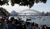 Lidé sedí na Mrs Macquaries Point s výhledem na operu v Sydney a most Sydney Harbour Bridge před silvestrovským ohňostrojem.