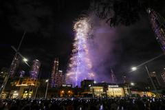 Lidé s mobily v rukou sledují novoroční ohňostroj v centru Dubaje.