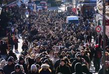 Stovky lidí, někteří s kyticemi v náručí, kráčely v klikatém průvodu kolem zavřených obchodů.