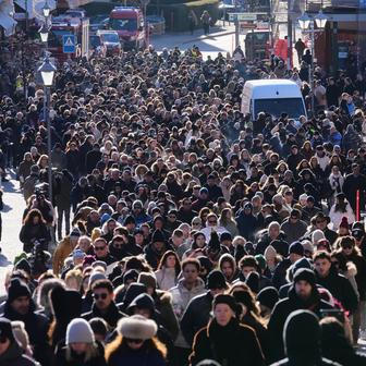 Stovky lidí, někteří s kyticemi v náručí, kráčely v klikatém průvodu kolem zavřených obchodů.