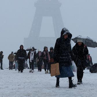 Lidé kráčí po zasněženém náměstí Trocadéro poblíž Eiffelovy věže, zatímco zimní počasí se sněhem a nízkými teplotami zasáhlo velkou část země.