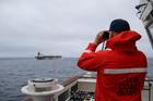 A U.S. Coast Guard official looks through binoculars at the ship Marinera (Ex-Bella 1)