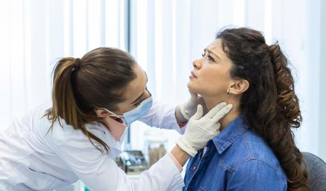 ["Endocrinologist examining throat of young woman in clinic. Women with thyroid gland test . Endocrinology, hormones and treatment. Inflammation of the sore throat"]