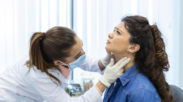 ["Endocrinologist examining throat of young woman in clinic. Women with thyroid gland test . Endocrinology, hormones and treatment. Inflammation of the sore throat"]