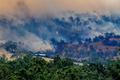 Smoke rises from a burning forest on a hillside behind a home near Longwood as bushfires continue to burn under severe fire weather conditions in Longwood