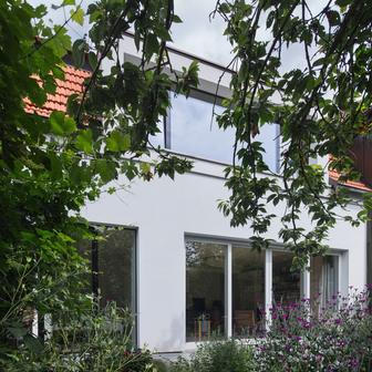 Největší změnu pak představuje vikýř v patře směrem do zahrady, který nahradil původní dva malé otvory. V interiéru díky němu proudí světlo a prostor se otevírá do zahrady. Prosklené dveře, odstraněné podhledy a nová práce s materiály dodaly vstupu vzdušnost. 