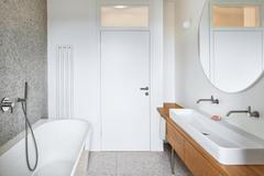 A co dál? Koupelny kombinují teracovou dlažbu, dubový nábytek a bílé velkoformátové obklady. 