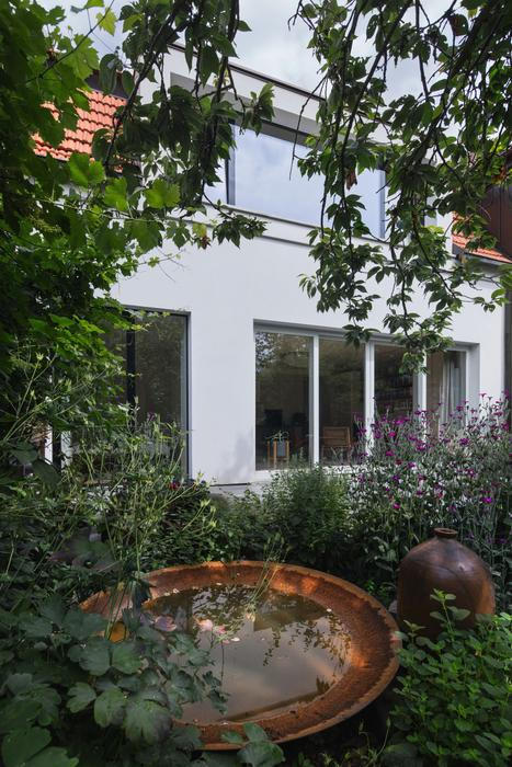 Největší změnu pak představuje vikýř v patře směrem do zahrady, který nahradil původní dva malé otvory. V interiéru díky němu proudí světlo a prostor se otevírá do zahrady. Prosklené dveře, odstraněné podhledy a nová práce s materiály dodaly vstupu vzdušnost. 