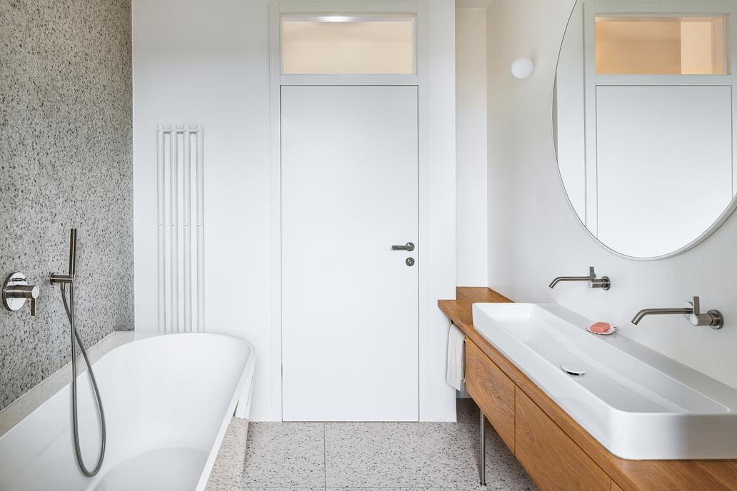 A co dál? Koupelny kombinují teracovou dlažbu, dubový nábytek a bílé velkoformátové obklady. 