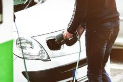 Man charging electric car at charging station