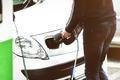 Man charging electric car at charging station