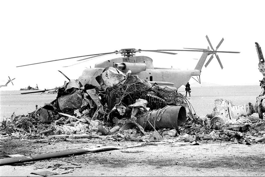 Trosky spáleného amerického vrtulníku leží před opuštěným strojem ve východní pouštní oblasti Íránu 27. dubna 1980, den po neúspěšném zásahu amerických komand DELTA, jehož cílem bylo osvobodit rukojmí z amerického velvyslanectví v Teheránu.
