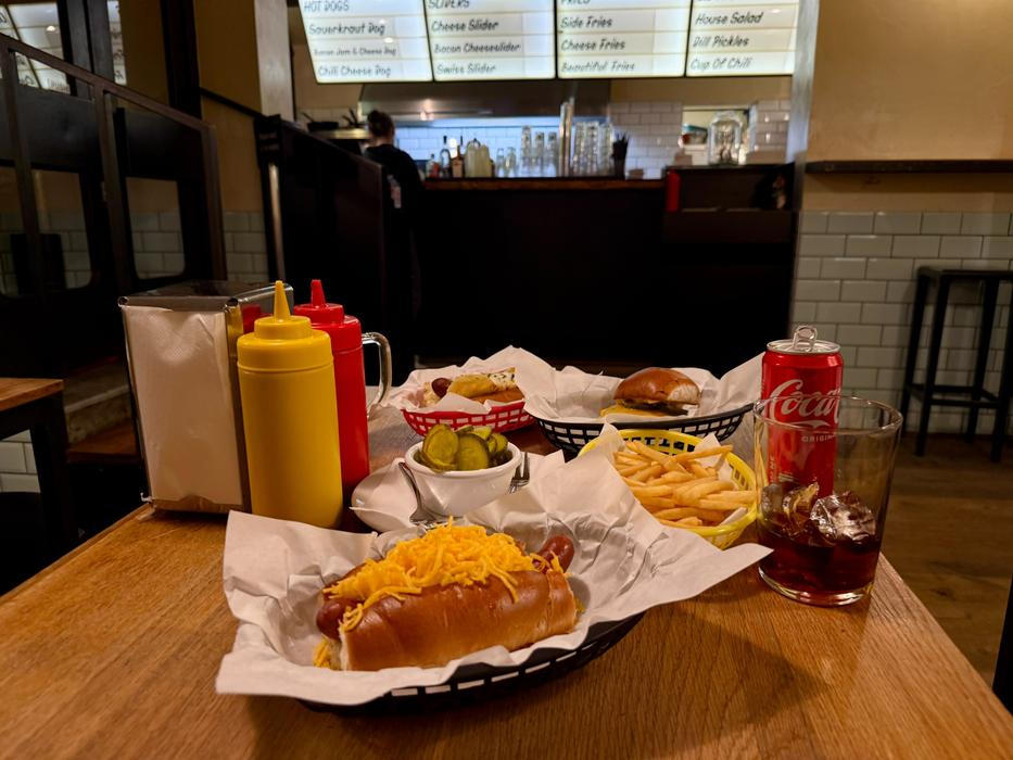 Kvalitní párek doplňuje sladká chuť slaninového džemu, hovězí slider je šťavnatý a chuťově vyvážený, hranolky jsou připraveny přesně tak akorát a nakládané okurky s koprem příjemně osvěžují a křupou.