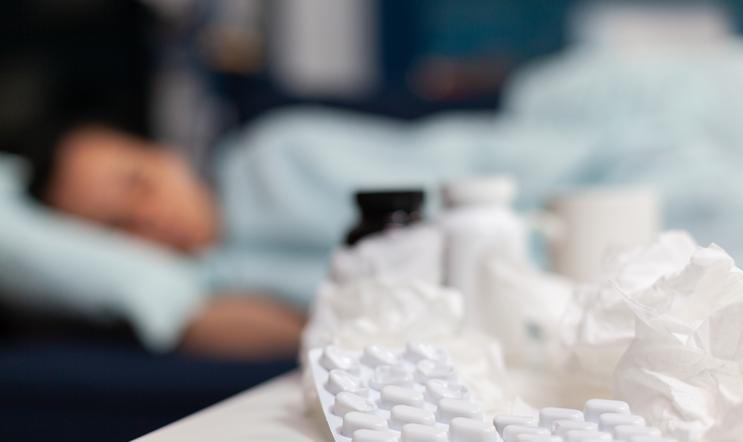 Close up of bottles and pills for sick woman with virus