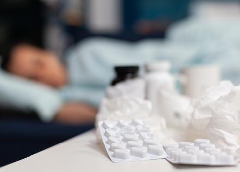 Close up of bottles and pills for sick woman with virus