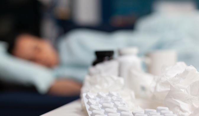 Close up of bottles and pills for sick woman with virus