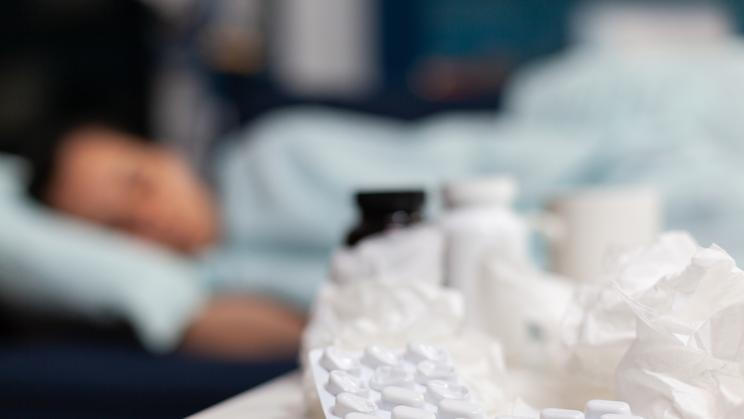 Close up of bottles and pills for sick woman with virus