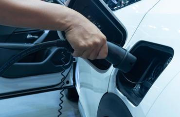 Midsection,Of,Man,Plugging,In,Cable,While,Charging,Electric,Car