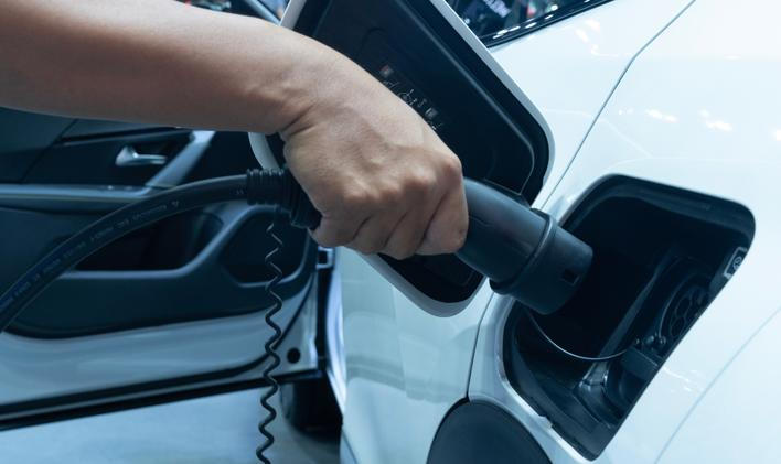 Midsection,Of,Man,Plugging,In,Cable,While,Charging,Electric,Car