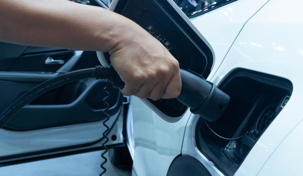 Midsection,Of,Man,Plugging,In,Cable,While,Charging,Electric,Car