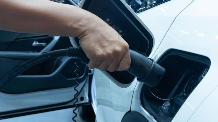 Midsection,Of,Man,Plugging,In,Cable,While,Charging,Electric,Car