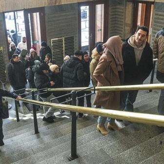 Městská knihovna v Praze a turisté čekající ve frontě na fotku se sloupem z knih kvůli jeho popularitě na sociálních sítích.