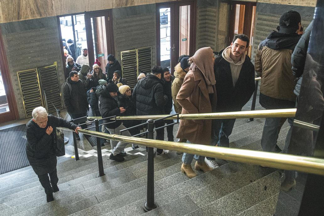 Městská knihovna v Praze a turisté čekající ve frontě na fotku se sloupem z knih kvůli jeho popularitě na sociálních sítích.