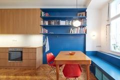 Největší místnost bytu propojuje kuchyň, jídelnu a obývací část do jednoho plynulého celku. Vestavný nábytek je řešen kolážovitě – lakovaná MDF zde nakombinovali s dubovou dýhou, což interiér odlehčuje a dodává mu osobitý charakter.