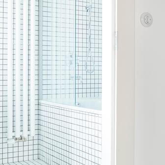 Stejně jako dispozice i koupelna prošla jen minimálními změnami. Posun příčky umožnil vznik komfortního prostoru s vanou a vestavnou skříňkou pod umyvadlem. Mozaikový obklad dodává místnosti lehkost a opticky ji zvětšuje, zatímco denní světlo z původního okna přináší nečekaný pocit vzdušnosti a klidu – kvalitu, která v městských bytech nebývá samozřejmostí.