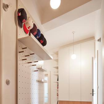 A co dál? Chodba, která často bývá opomíjená, je v tomto bytě víc než jen komunikačním prostorem – stává se praktickým centrem bytu, kde se potkává úložná kapacita s estetikou. Botník, kombinovaná skříň a systémová stěna s otvory pro police a háčky se objevují i v dalších částech interiéru a sjednocují ho vizuálně i funkčně. A cementová dlažba podtrhuje historizující atmosféru a zároveň plynule propojuje vstupní část s ostatními místnostmi.