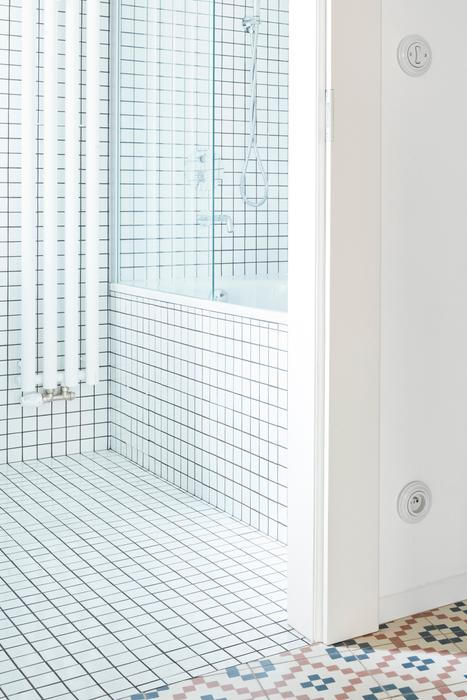 Stejně jako dispozice i koupelna prošla jen minimálními změnami. Posun příčky umožnil vznik komfortního prostoru s vanou a vestavnou skříňkou pod umyvadlem. Mozaikový obklad dodává místnosti lehkost a opticky ji zvětšuje, zatímco denní světlo z původního okna přináší nečekaný pocit vzdušnosti a klidu – kvalitu, která v městských bytech nebývá samozřejmostí.