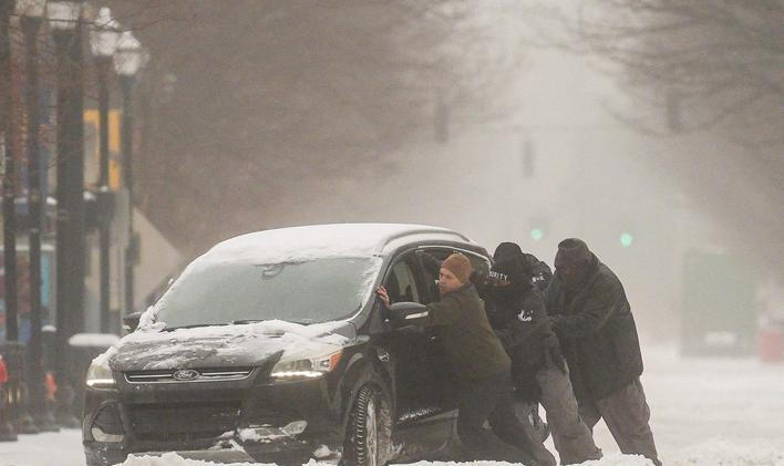 A group of men try to help a stuck motorist in the snow while the multi-state Winter Storm Fern hits the metro area of Louisville