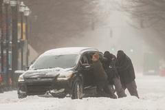 A group of men try to help a stuck motorist in the snow while the multi-state Winter Storm Fern hits the metro area of Louisville