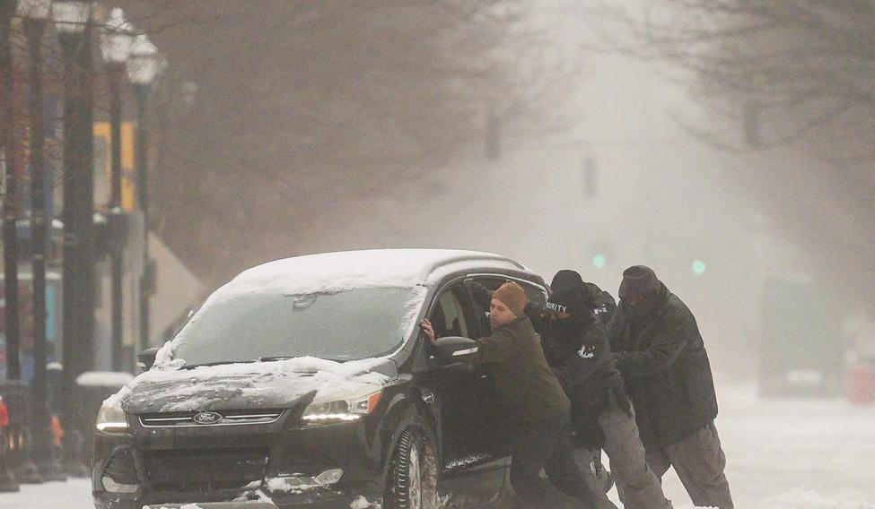 A group of men try to help a stuck motorist in the snow while the multi-state Winter Storm Fern hits the metro area of Louisville