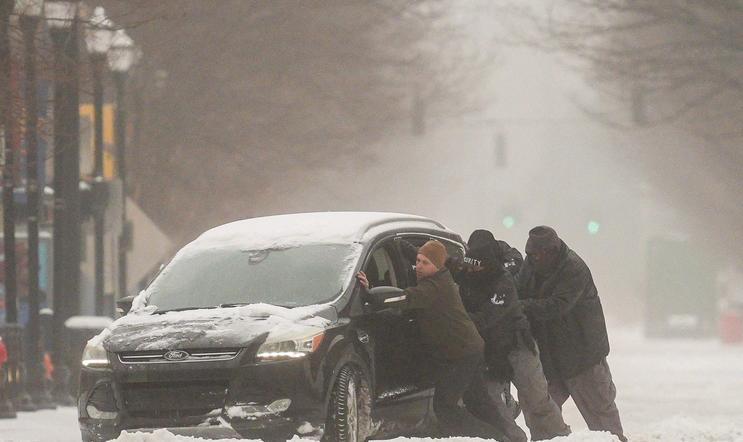 A group of men try to help a stuck motorist in the snow while the multi-state Winter Storm Fern hits the metro area of Louisville