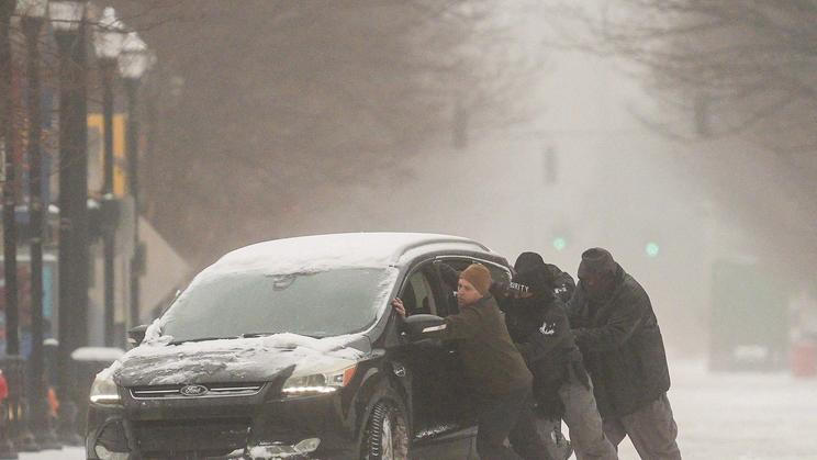 A group of men try to help a stuck motorist in the snow while the multi-state Winter Storm Fern hits the metro area of Louisville