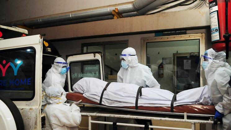 Indičtí zdravotníci v ochranných oblecích přenášejí tělo člověka, který v roce 2023 zemřel na infekci virem Nipah v indickém státě Kérala.